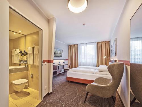 a hotel room with a bed and a chair at Best Western Hotel Wetzlar in Wetzlar