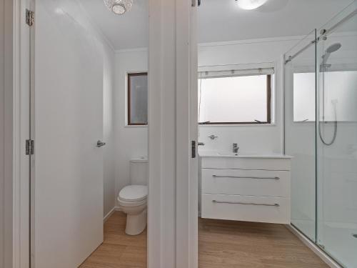 a bathroom with a toilet and a glass shower at Beachfront Beauty - Whangamata Beachfront Home in Whangamata