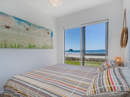 a bedroom with a bed and a large window at Beachfront Beauty - Whangamata Beachfront Home in Whangamata