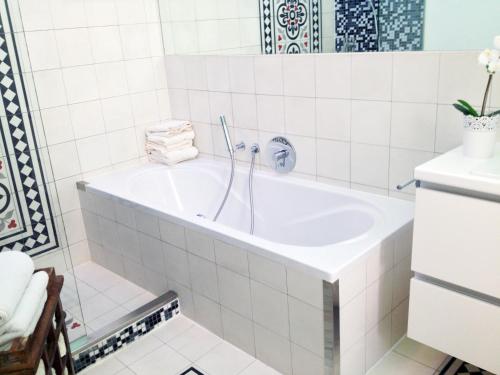 a bath tub in a white tiled bathroom at Big Vintage Style Flat Near Schönbrunn in Vienna