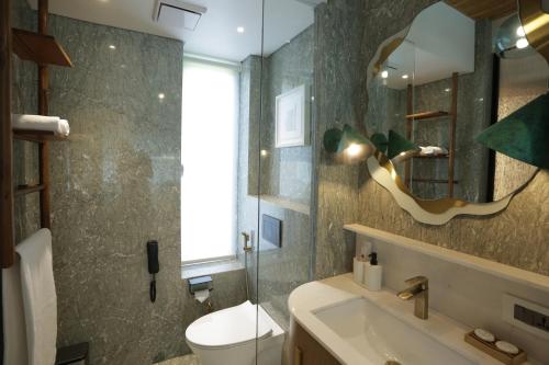 a bathroom with a sink and a toilet and a mirror at Regency Hotel Malabar Hill in Mumbai