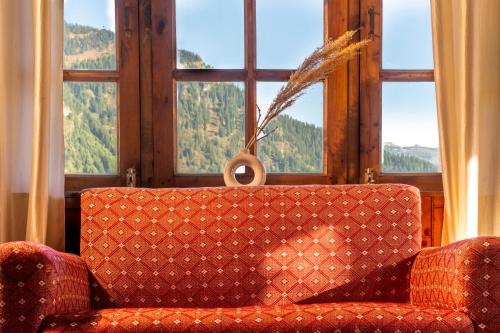 a couch sitting in front of a large window at Timberwolves Vintage Manali in Manāli