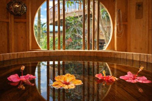 a pool with three flowers sitting on top of it at Island Breeze - Round House with BBQ - Wooden Hot Tub - Beach in Onna
