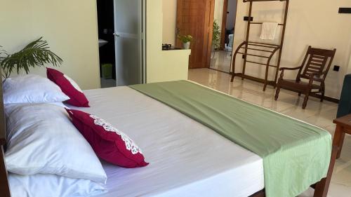 a large bed with red and white pillows at Handagedara Madiha Villa in Matara
