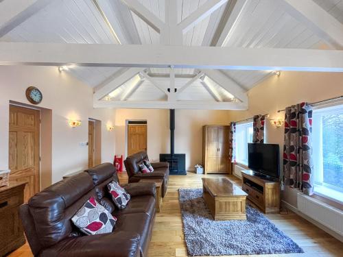 a living room with a leather couch and a tv at Pilots Loft in Menai Bridge