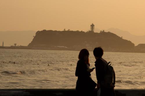 two people standing on the beach near the water at Enoshima Guest House 134 in Fujisawa