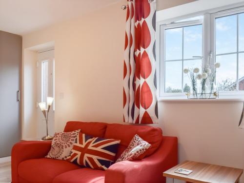 a red couch in a living room with a window at The Old Dairy in Nether Broughton