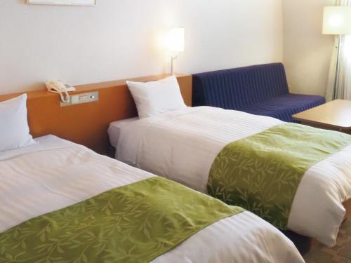 a hotel room with two beds and a couch at Hotel Hiroshima Sunplaza in Hiroshima