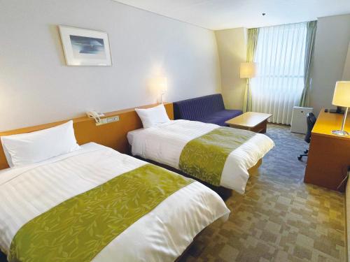 a hotel room with two beds and a chair at Hotel Hiroshima Sunplaza in Hiroshima