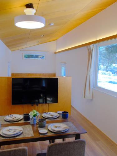a dining room with a table and a television at 雪箱神楽 Yukibako Kagura 一棟貸切かぐらスキー場徒歩7分 in Yuzawa