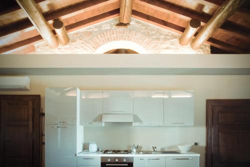 佩斯基耶拉德爾加爾達的住宿－吉拉迪公寓，厨房配有白色橱柜和砖砌天花板