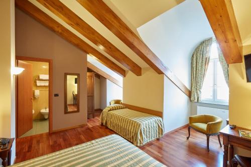 a hotel room with two beds and a chair at Liberty Hotel in Turin