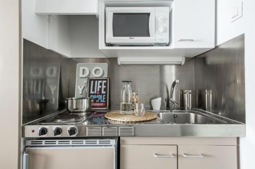 cocina con fregadero y microondas en Residencia Universitaria Roberto de Nobili, en Sant Cugat del Vallès