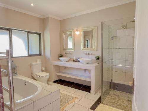 a bathroom with two sinks and a tub and a shower at Amoris Guesthouse - Waterkloof ridge in Pretoria