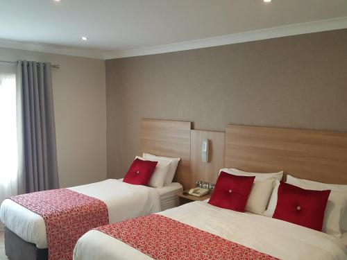 two beds in a hotel room with red pillows at The Lodge Hotel in Coleraine