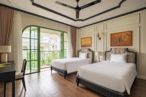 a bedroom with two beds and a desk and a window at Villa Vanda Phu Quoc in Phú Quốc