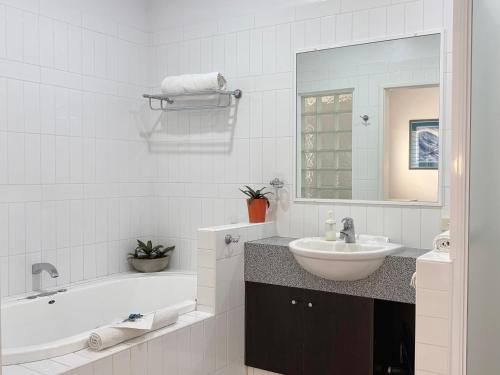 a white bathroom with a tub and a sink at Gecko Lodge Kalbarri in Kalbarri