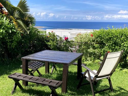 a wooden table and two chairs and the ocean at Vacances a la mer Ishigaki in Ishigaki Island