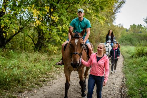a man riding a horse and a girl walking down a dirt road at Rezort u Bobiho in Nový Tekov
