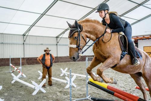 a woman riding a horse jumping over an obstacle at Rezort u Bobiho in Nový Tekov