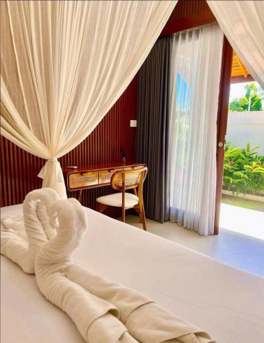 a room with a bed with a chair and a table at Parama Swaha Villa Near Canggu in Munggu
