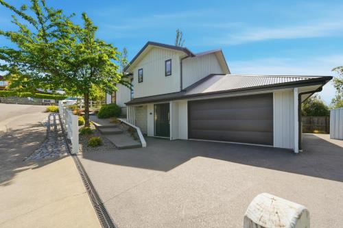 a house with a garage and a driveway at Rolki House - Hanmer Springs Holiday Home in Hanmer Springs