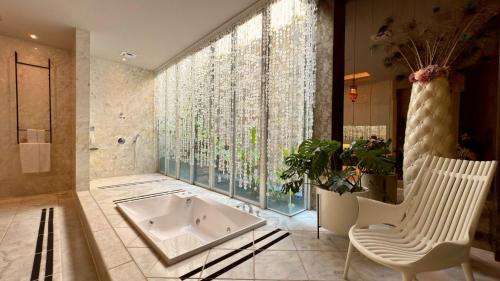 a bathroom with a tub and a chair and a window at 沐蘭精品旅館-台北大直館 Mulan Boutique Hotel in Taipei