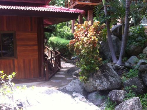 a path leading to a building with a tree and rocks at Venus Resort in Haad Rin