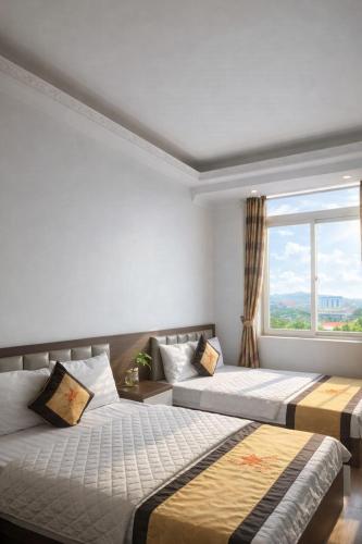 two beds in a room with a window at Crown Hotel in Thái Nguyên