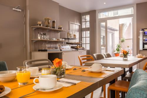 a dining room with a table and chairs and a kitchen at Paris d'Issy Hôtel Porte de Versailles in Issy-les-Moulineaux