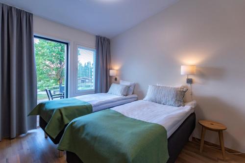 two beds in a hotel room with a window at Lohja Spa & Resort in Karjalohja