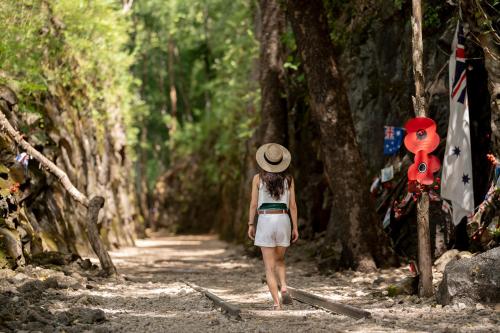 a woman in a hat walking down a forest path at Hintok River Camp in Sai Yok