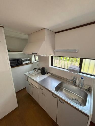 a small kitchen with a sink and a window at 丸亀 Sawau 丸亀駅まで徒歩8分 うどん屋まで徒歩1分 5名まで宿泊可駐車場 1台有 港近 in Marugame