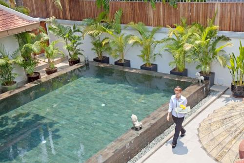 a woman is standing next to a swimming pool at The Pavilion in Phnom Penh