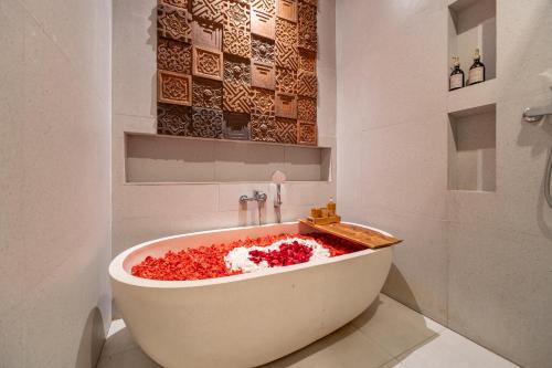 a bath tub filled with red flowers in a bathroom at The Hita Apartement in Seminyak