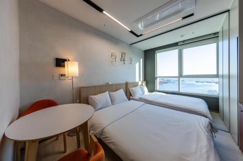 a bedroom with a bed and a table and a window at Nampo Stay 99 in Busan