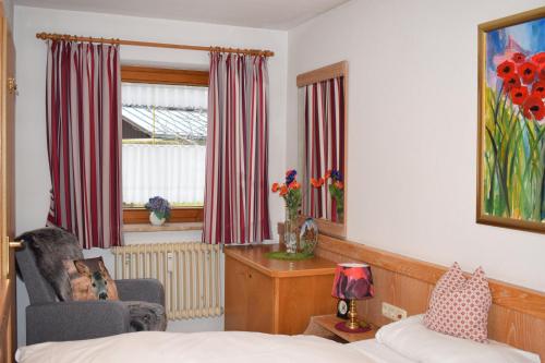a bedroom with a bed and a chair and a window at Allgäuschönheit inkl BadHindelangPlus Karte in Bad Hindelang