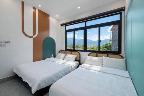 two beds in a room with a large window at Tom Homestay Cao Bang - Motorbike rental in Cao Bằng