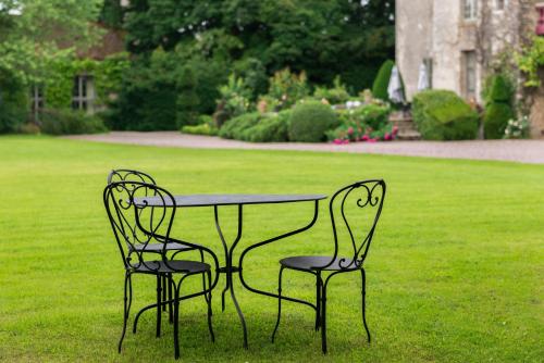 two chairs and a table in the grass at Château de Saint Paterne in Saint-Paterne