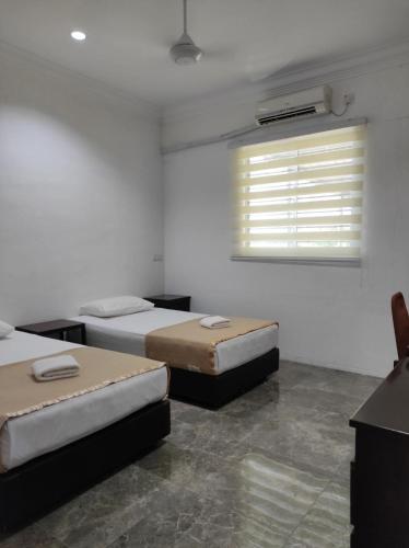 a room with two beds and a window with blinds at House 21 in Lahad Datu