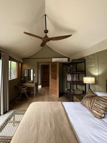 a bedroom with a ceiling fan and a bed at Mkhuze Trails Lodge in Hluhluwe