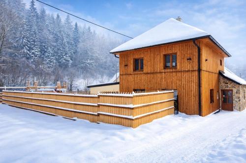 a wooden cabin in the snow with a fence at Chalupa Herbortice in Cotkytle