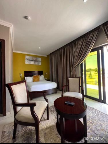 a bedroom with a bed and two chairs and a table at Voyager Inn-Hotel in Palatswe