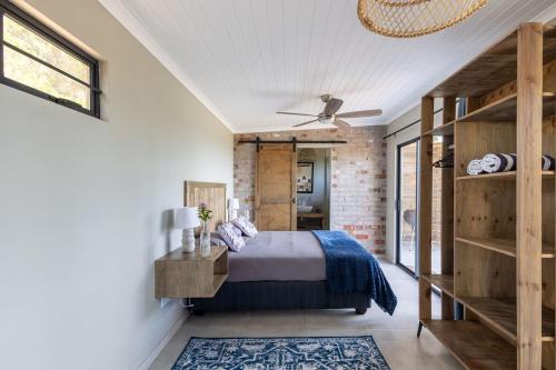 a bedroom with a bed and a brick wall at Myrtle Forest Retreat Cabin in Plettenberg Bay