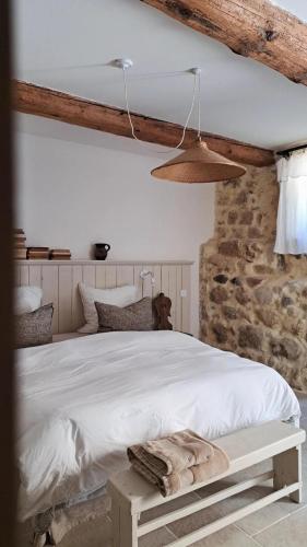 a bedroom with a white bed and a stone wall at La Potentille in Lieuran-Cabrières