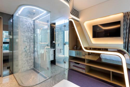 a bathroom with a walk in shower and a television at Butterfly on LKF, Central in Hong Kong