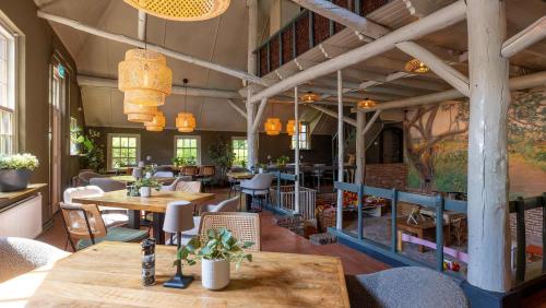 a restaurant with tables and chairs in a room at Molecaten Park De Leemkule in Hattem
