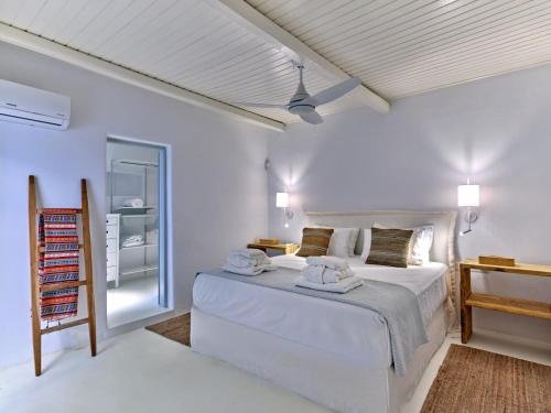 a white bedroom with a bed and a ceiling fan at Beach House Mikri Santa Maria in Kournonísi