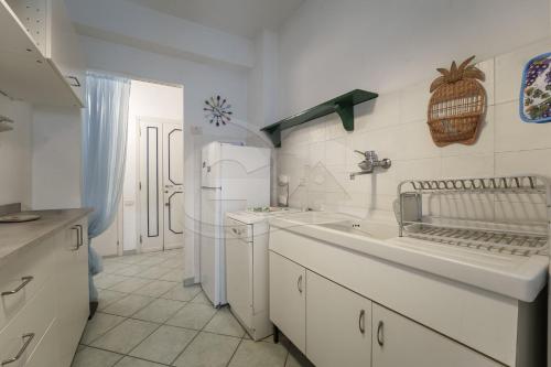 a white kitchen with a sink and a refrigerator at Casa Malu in Marina di Campo