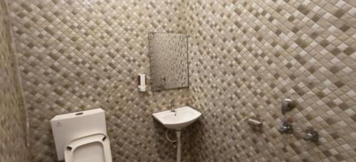 a bathroom with a sink and a toilet and a mirror at Hotel Utsav in Khatīma